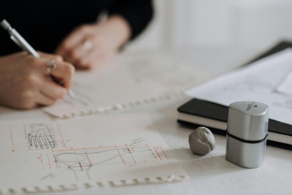 Detailed hand sketching on architectural blueprints with drawing tools and notebook.